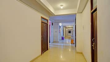 Un pasillo de hotel con suelo de baldosas, puertas de madera y una lámpara en el techo.