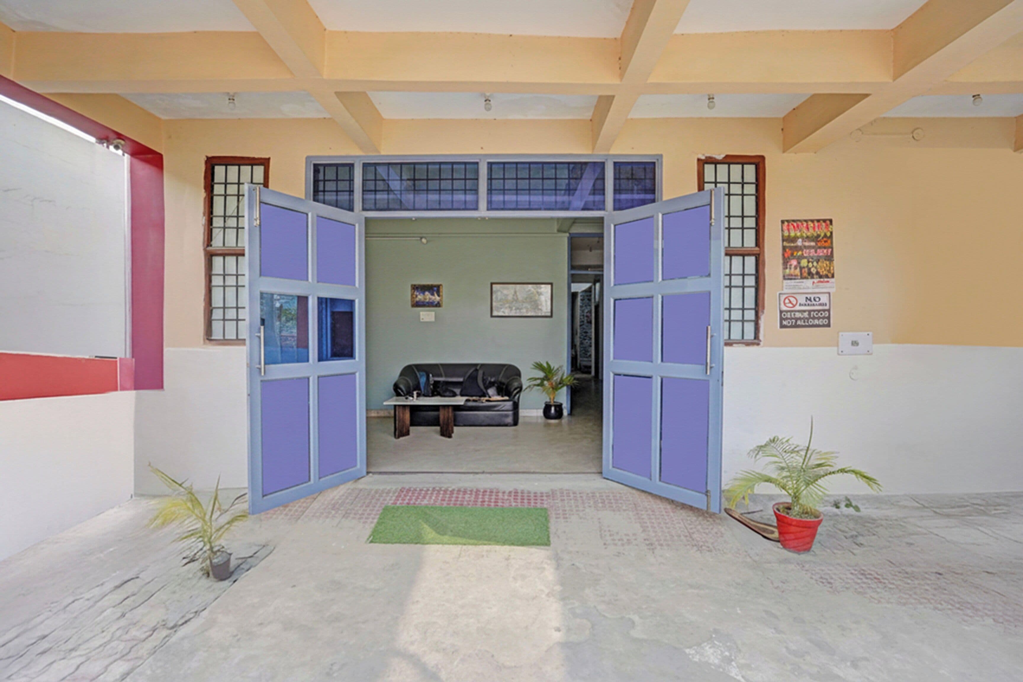 Una habitación con un sofá, dos plantas en macetas y una pequeña mesa.