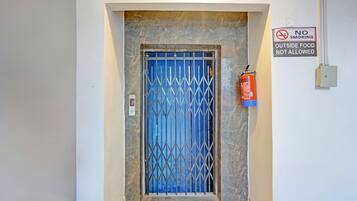 Una puerta con una reja de metal, un extintor en la pared y un cartel de 'NO FUMAR'.