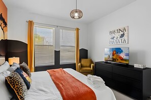 A hotel room with a bed, a television, a chair, and artwork on the walls. - 6BR Disney-themed Villa + Pool & Game Room (Kissimmee)