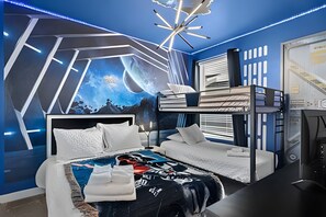 A modern bedroom with a bunk bed, a large wall mural, and a unique ceiling light fixture. - 6BR Disney-themed Villa + Pool & Game Room (Kissimmee)