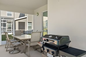 A modern outdoor kitchen with a gas stove, dining chairs, and a table. - 6BR Disney-themed Villa + Pool & Game Room (Kissimmee)