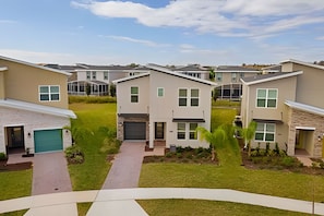 A modern residential complex with multiple two-story houses, each featuring a garage, a covered patio, and a well-maintained lawn. - 6BR Disney-themed Villa + Pool & Game Room (Kissimmee)