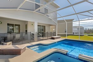 An indoor swimming pool with a glass enclosure, a covered seating area, and a view of the outdoors. - 6BR Disney-themed Villa + Pool & Game Room (Kissimmee)
