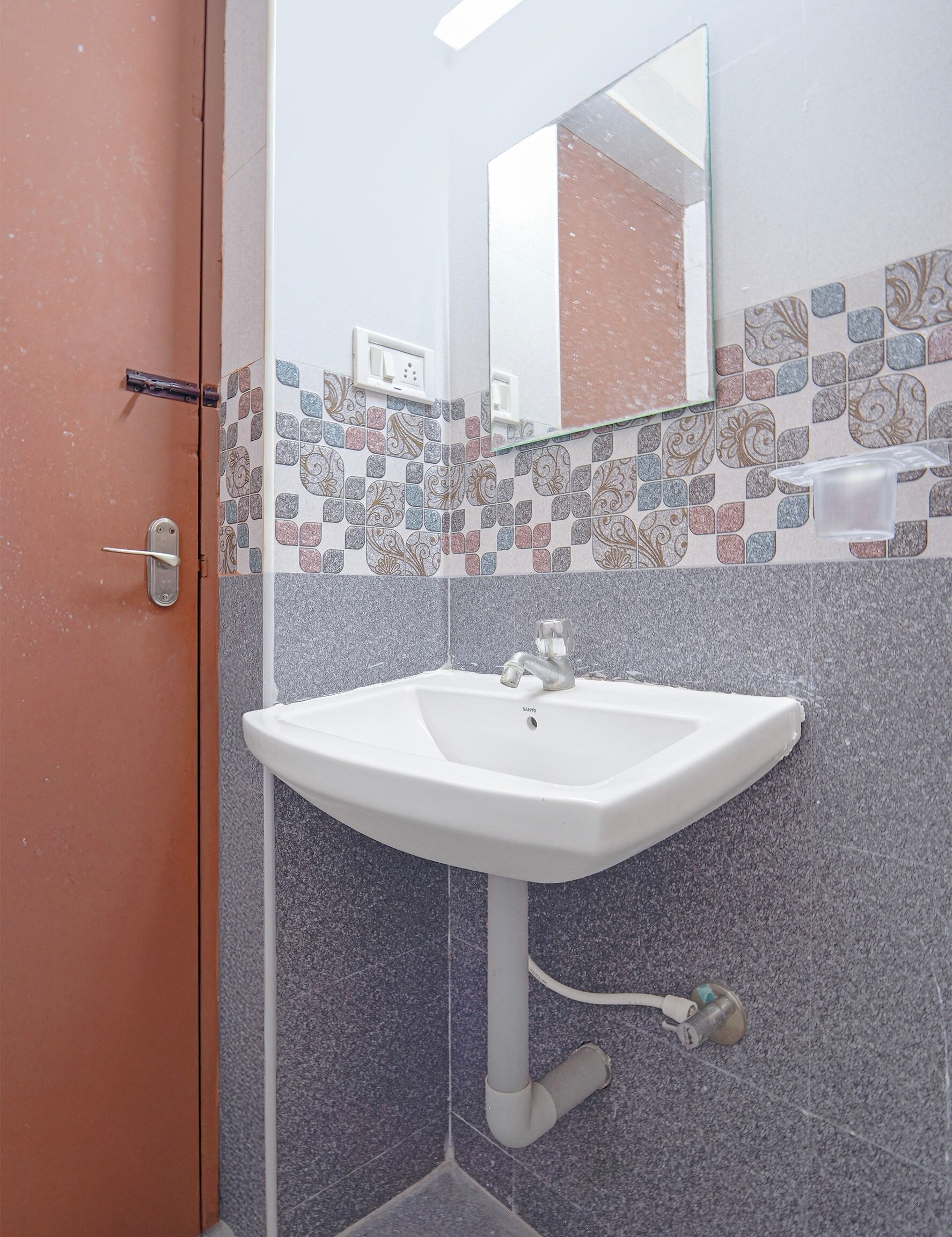 A bathroom with a white sink, a mirror, and a door with a handle.