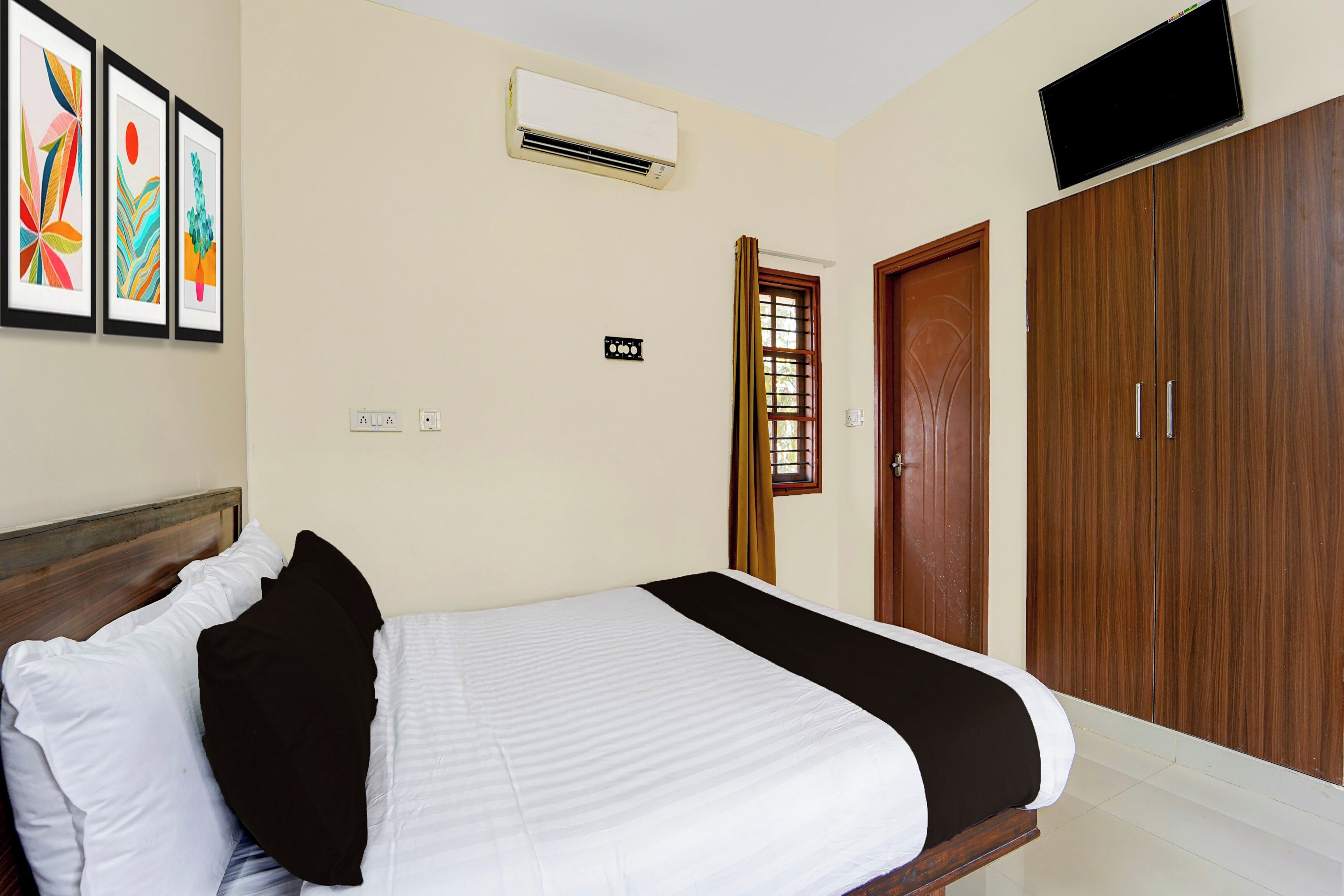 Una habitación de hotel con cama, armario, aire acondicionado y televisor.