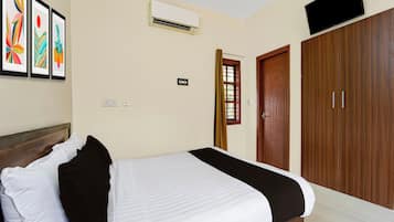 Una habitación de hotel con cama, armario, aire acondicionado y televisor.