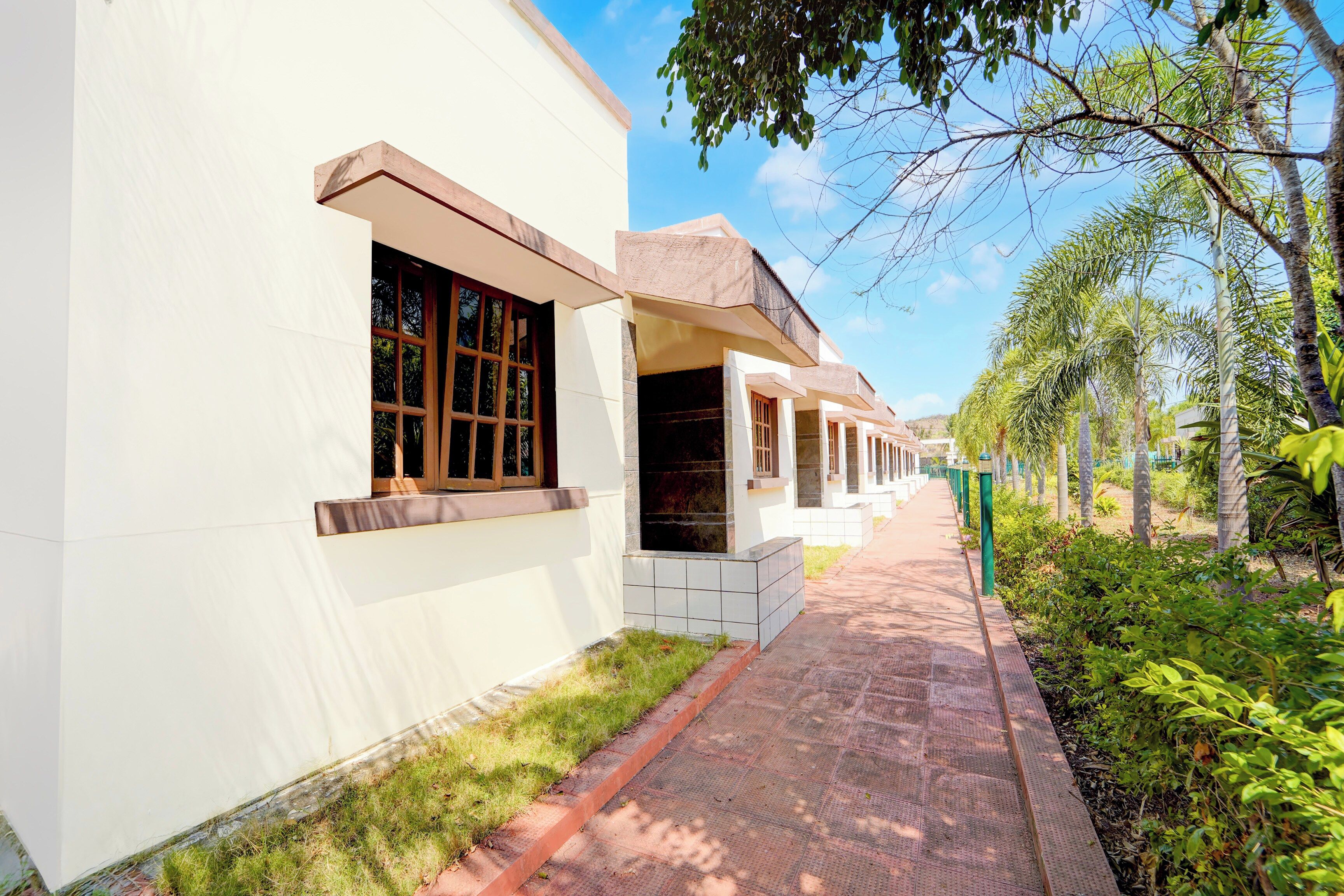 A pathway leading to a row of white buildings with large windows and a clear sky.
