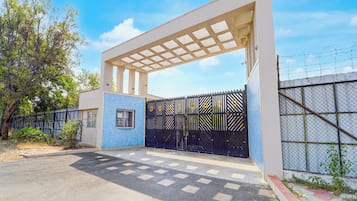 Una entrada protegida con un portón metálico y un corredor cubierto.