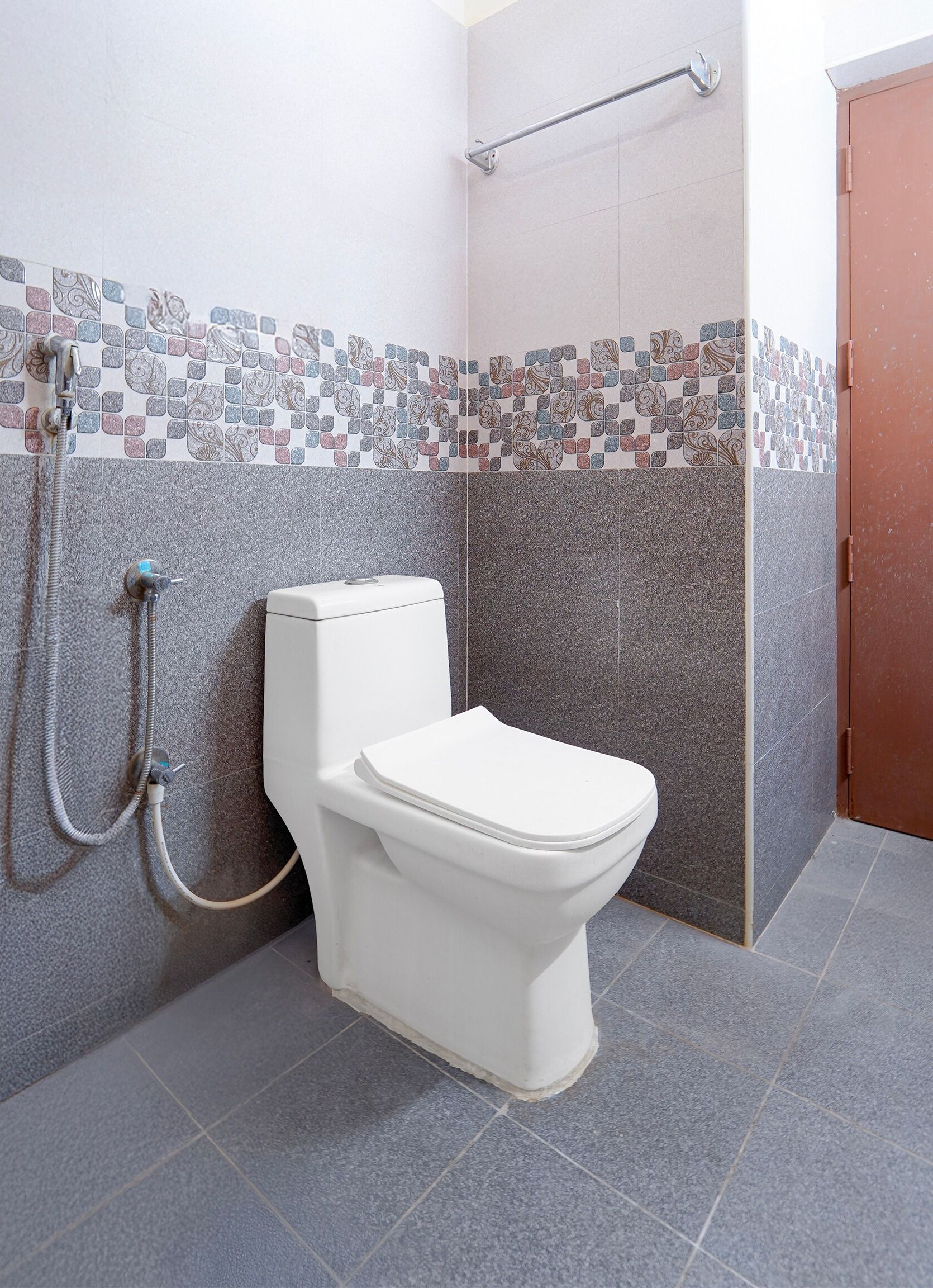 Un baño con inodoro, ducha y paredes de azulejos.
