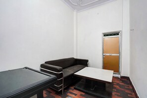 A small, sparsely furnished room with a sofa, a table, and a door. - Hotel O Sector 12 Ghaziabad (Ghaziabad)