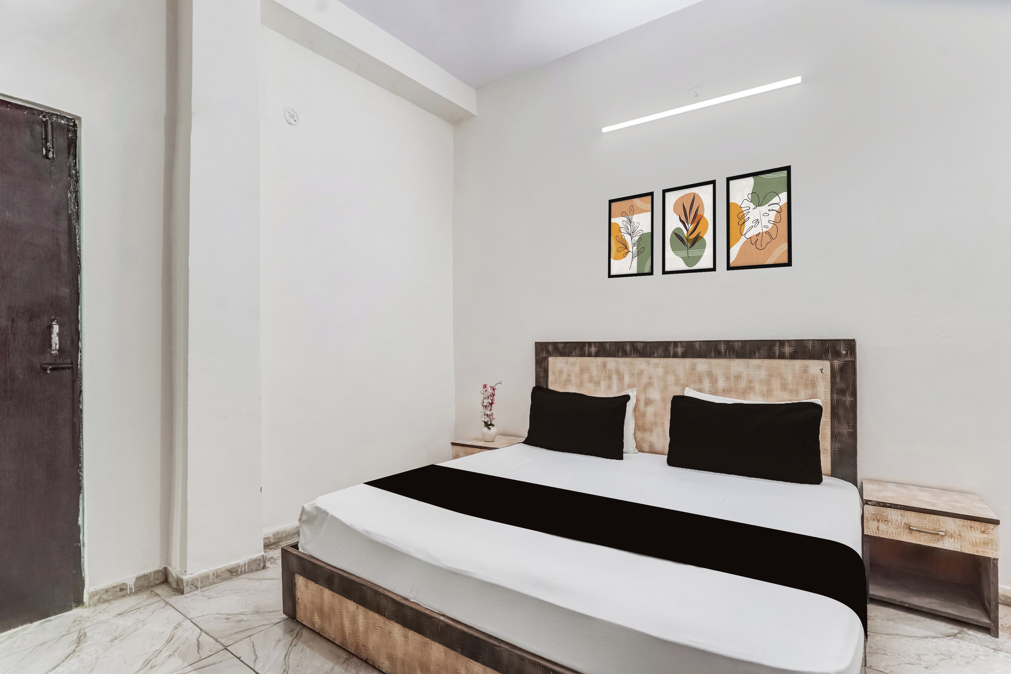 Habitación de hotel con cama, mesita de noche y lámpara fijada a la pared.