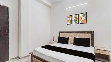 Habitación de hotel con cama, mesita de noche y lámpara fijada a la pared.