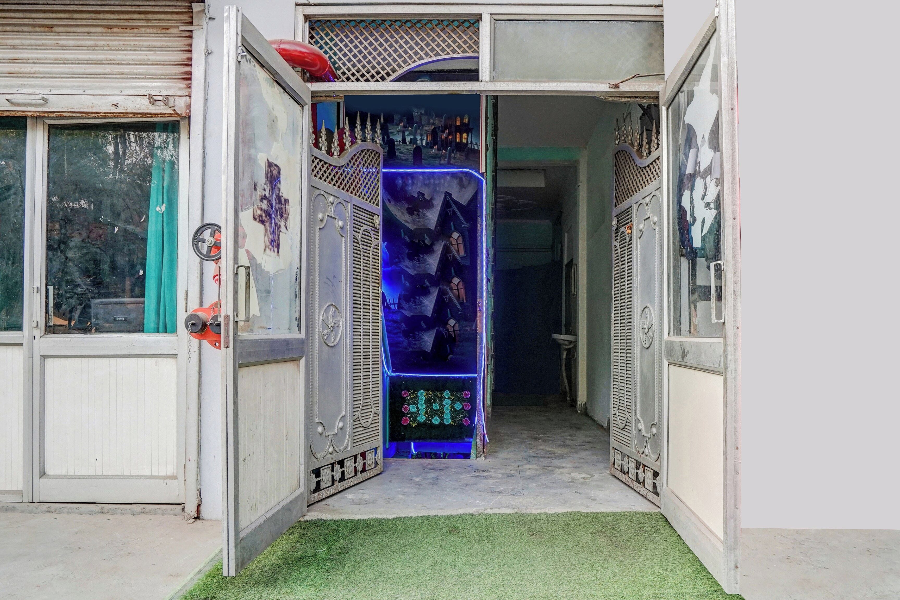 An open doorway with a decorative metal gate, a small step leading into a room, and a green artificial turf floor.