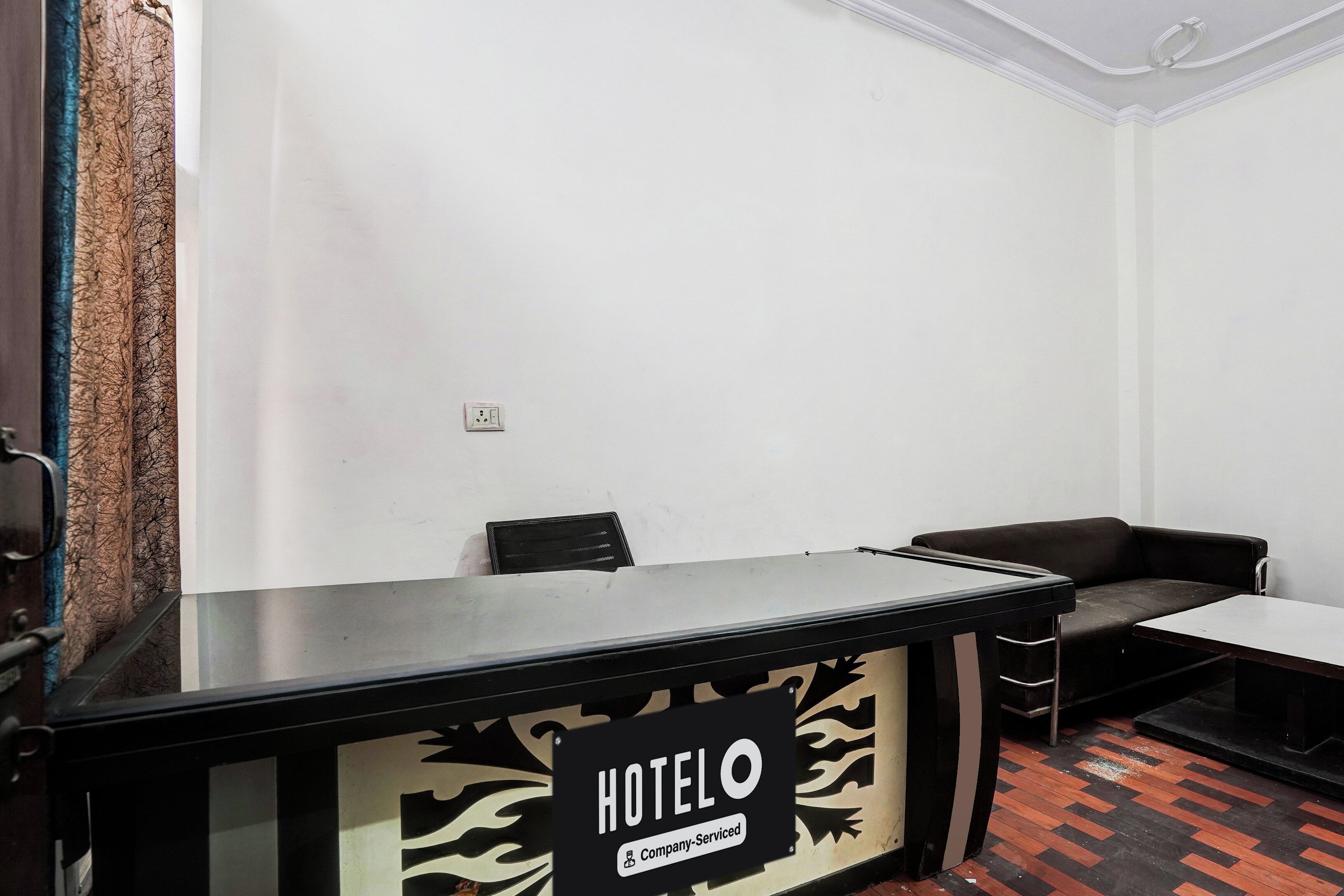 En hotellreception med en skylt som visar att den bemannas av företagets personal. I rummet finns två stolar och en soffa.