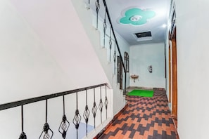 A staircase with a patterned floor, a handrail, and a ceiling with a decorative design. - Hotel O Sector 12 Ghaziabad (Ghaziabad)
