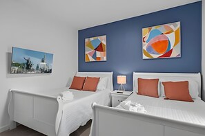 Habitació d'hotel amb dos llits, una tauleta de nit i art abstracte a les parets.