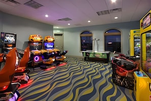 Ein Spielbereich mit Spielautomaten, einem Billardtisch und einem Fernseher.