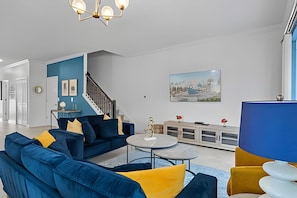 Un saló modern amb un sofà blau, una taula de centre rodona i un armari blau.