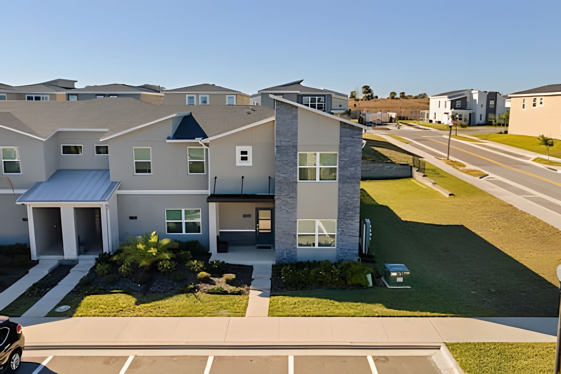 A modern multi-story residential building with a flat roof, large windows, and a well-maintained lawn.