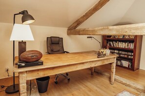 A room with a wooden desk, a leather chair, a lamp, a bookshelf, and a football. - New Listing (Rouède)
