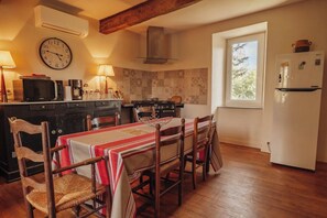 A kitchen with a dining table, chairs, a clock, a stove, and a refrigerator. - New Listing (Rouède)