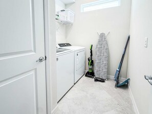 A laundry room with a washing machine, a drying rack, and a broom. - Windsor Cay 5BR Villa w/ Pool & Game Room (Clermont)