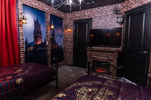A room with a brick wall, a fireplace, a television, and two beds with themed bedding. - Windsor Cay 5BR Villa w/ Pool & Game Room (Clermont)