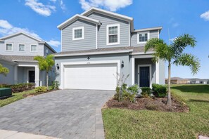 A two-story house with a garage, a driveway, and a well-maintained lawn with palm trees. - Disney Escape, Family Retreat, Private Pool (Davenport)