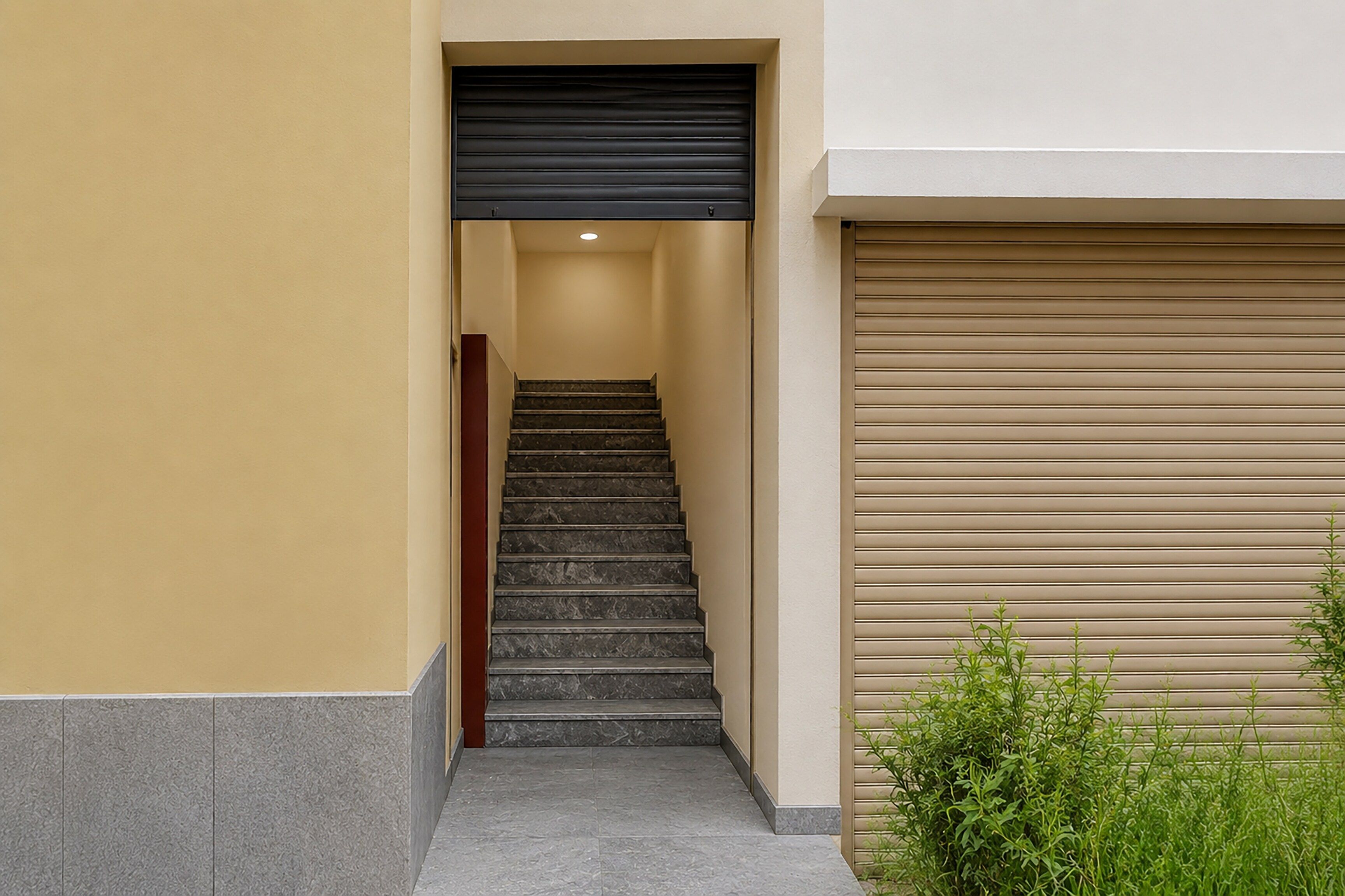 Una escalera estrecha que conduce a un rellano con una puerta con contraventanas cerrada arriba y otra puerta con contraventanas cerrada a la derecha.