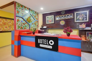 A hotel reception desk with a colorful design, a clock, and various framed artworks on the wall. - Hotel O James Street Railway Station (Hyderabad)