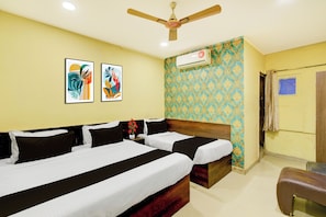 Quarto de hotel com cama, ventoinha no teto, duas obras de arte emolduradas, papel de parede estampado e ar condicionado.