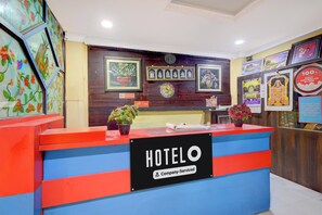 Taulell de recepció d'hotel amb un cartell que diu 'HOTELO', quadres a la paret i un cartell de 'No Fumar'.