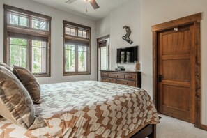 A bedroom with a bed, dresser, TV, and a wooden door. - Private Hot Tub | On Golf Course (Mammoth Lakes)
