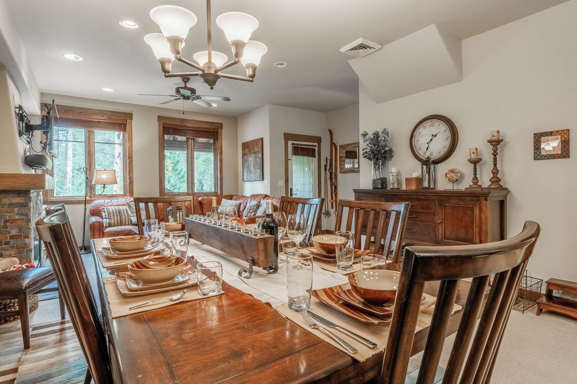 A dining room with a wooden table set for a meal, a chandelier, and a fireplace.