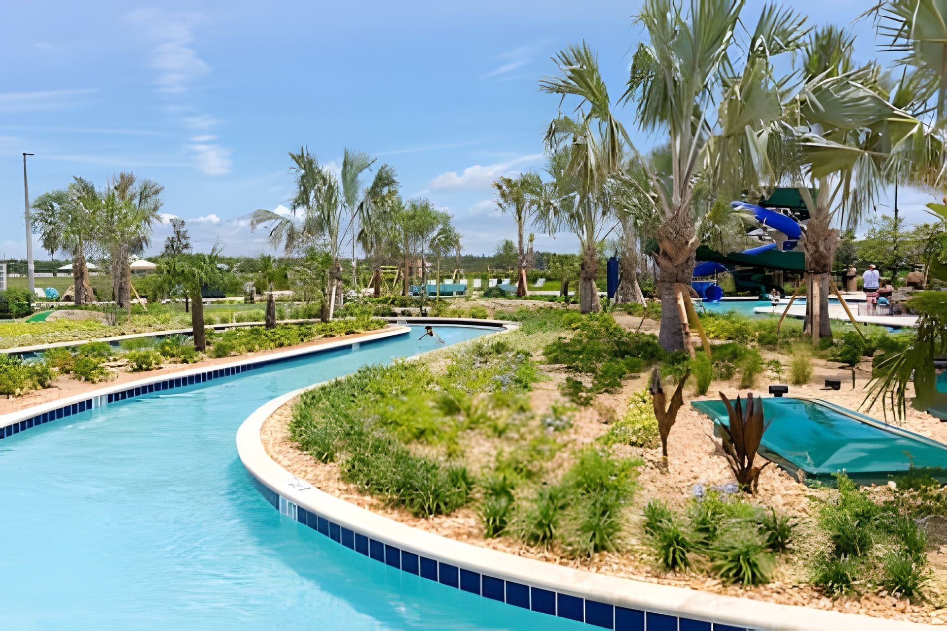 A pool area with multiple swimming pools, palm trees, and a water slide.