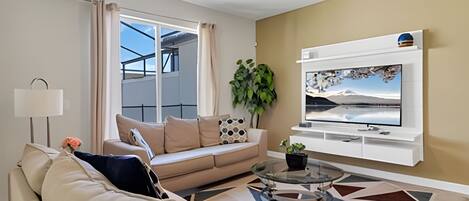 A modern living room with a sofa, a coffee table, and a TV mounted on the wall.