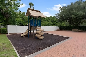 A playground with a slide, climbing structure, and tire swings. - 3BR Lucaya Village Home Near Disney (Kissimmee)