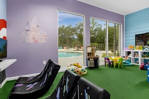 A room with a pool view, a desk with a computer, and a play area with toys. - 3BR Lucaya Village Home Near Disney (Kissimmee)