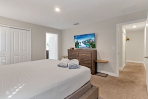 A bedroom with a bed, a dresser, a painting, and a door leading to another room. - 4BR Storey Lake Home With Private Pool (Kissimmee)
