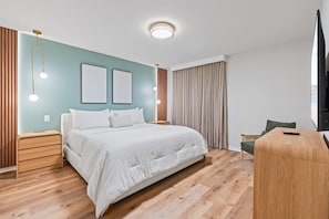 A modern hotel room with a large bed, wooden nightstands, a desk, and a television. - Luxury 5BR Villa With Pool and Themed Bedrooms (Clermont)