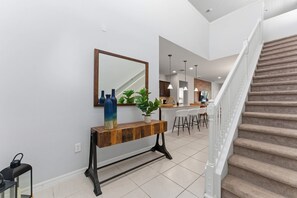 A modern interior with a wooden console table, a mirror, and a staircase. - 6BR Family Home With Pool and Game Room (Kissimmee)