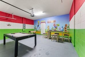 A pool table in a room with green and red walls, a Mario-themed mural, and a Nintendo World sign. - 6BR Family Home With Pool and Game Room (Kissimmee)