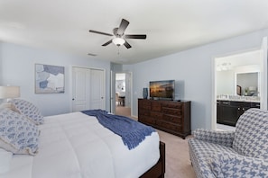 A bedroom with a bed, a dresser, a chair, a ceiling fan, and a television. - 6BR Family Home With Pool and Game Room (Kissimmee)