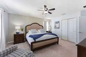 A bedroom with a bed, nightstands, a ceiling fan, a dresser, and a chair. - 6BR Family Home With Pool and Game Room (Kissimmee)