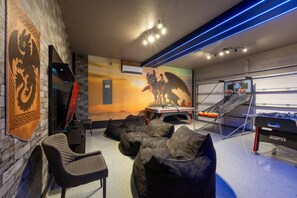 Quarto com um mural, mesa de pebolim e puffs.