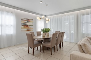 Uma área de jantar moderna com uma mesa redonda, seis cadeiras e um lustre.