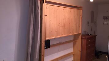Ein Zimmer mit einem Holzschrank, einer weißen Wand und einem roten Vorhang.