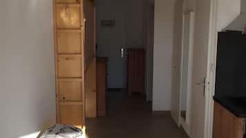 En hall med trädörrar, en säng med ett mönstrat överkast och ett litet skåp.
