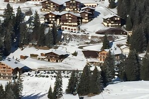 En snötäckt bergsby med flera byggnader i chaletstil.